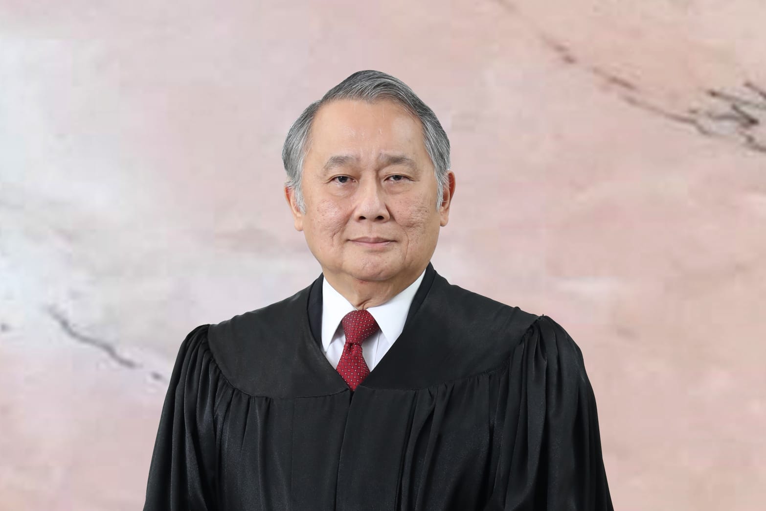Man with gray hair in black judicial robe and red tie.